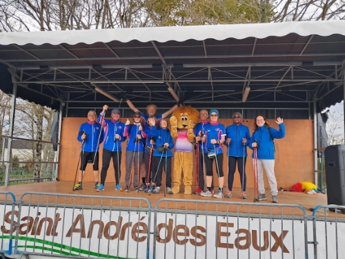 Groupe de pratiquants de marche nordique sur une scène à Saint-André-des-Eaux avec une mascotte