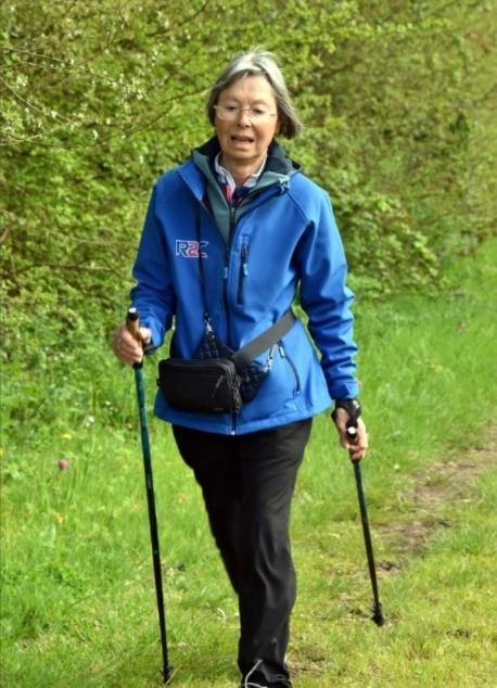 Femme pratiquant la marche nordique sur un chemin verdoyant à Saint-André-des-Eaux avec des bâtons de marche